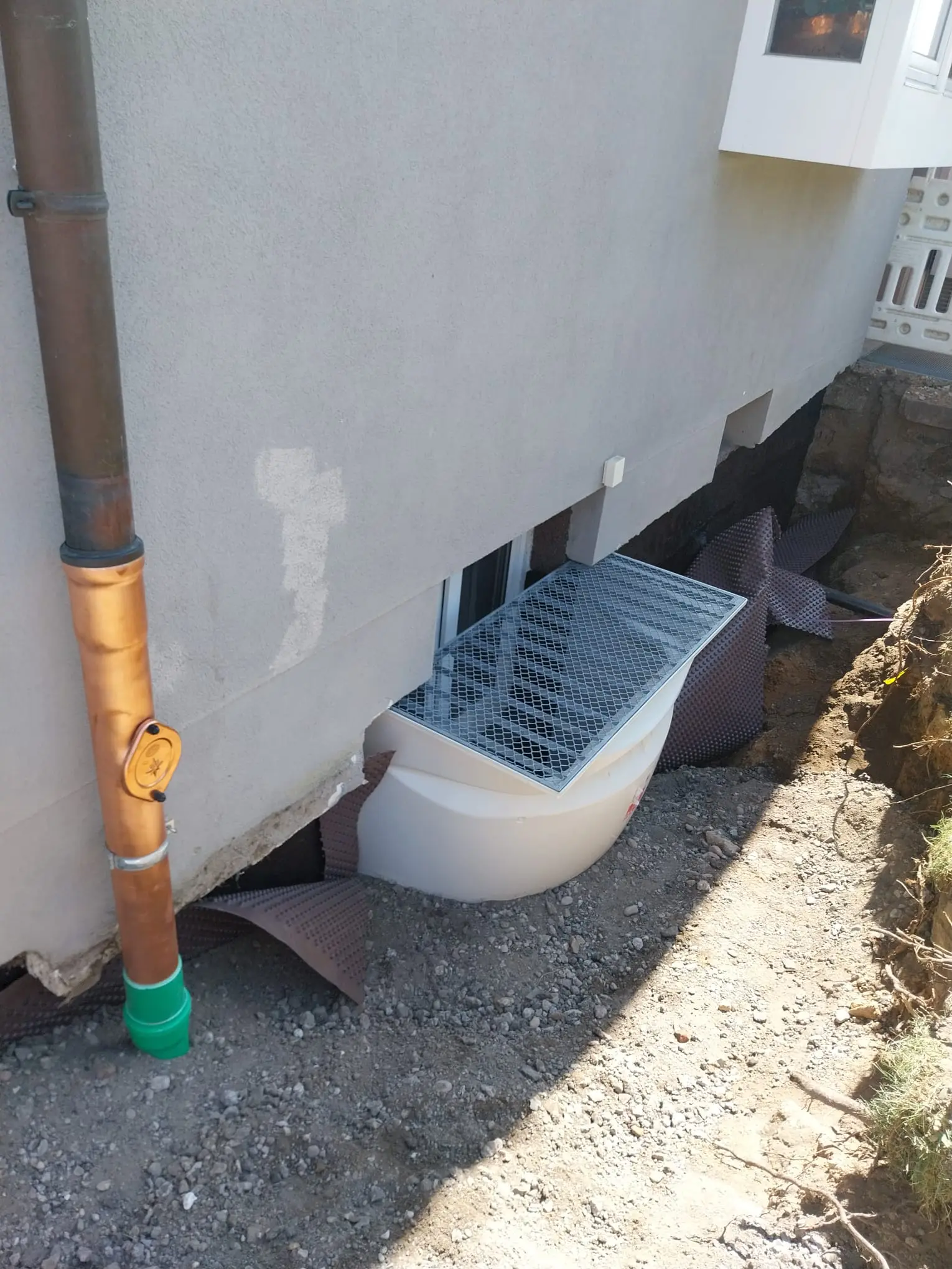 Setzen Lichtschacht an Kelleraußenwand nach Isolierungsarbeiten am Haus; Kupferstandrohr mit Revisionsöffnung