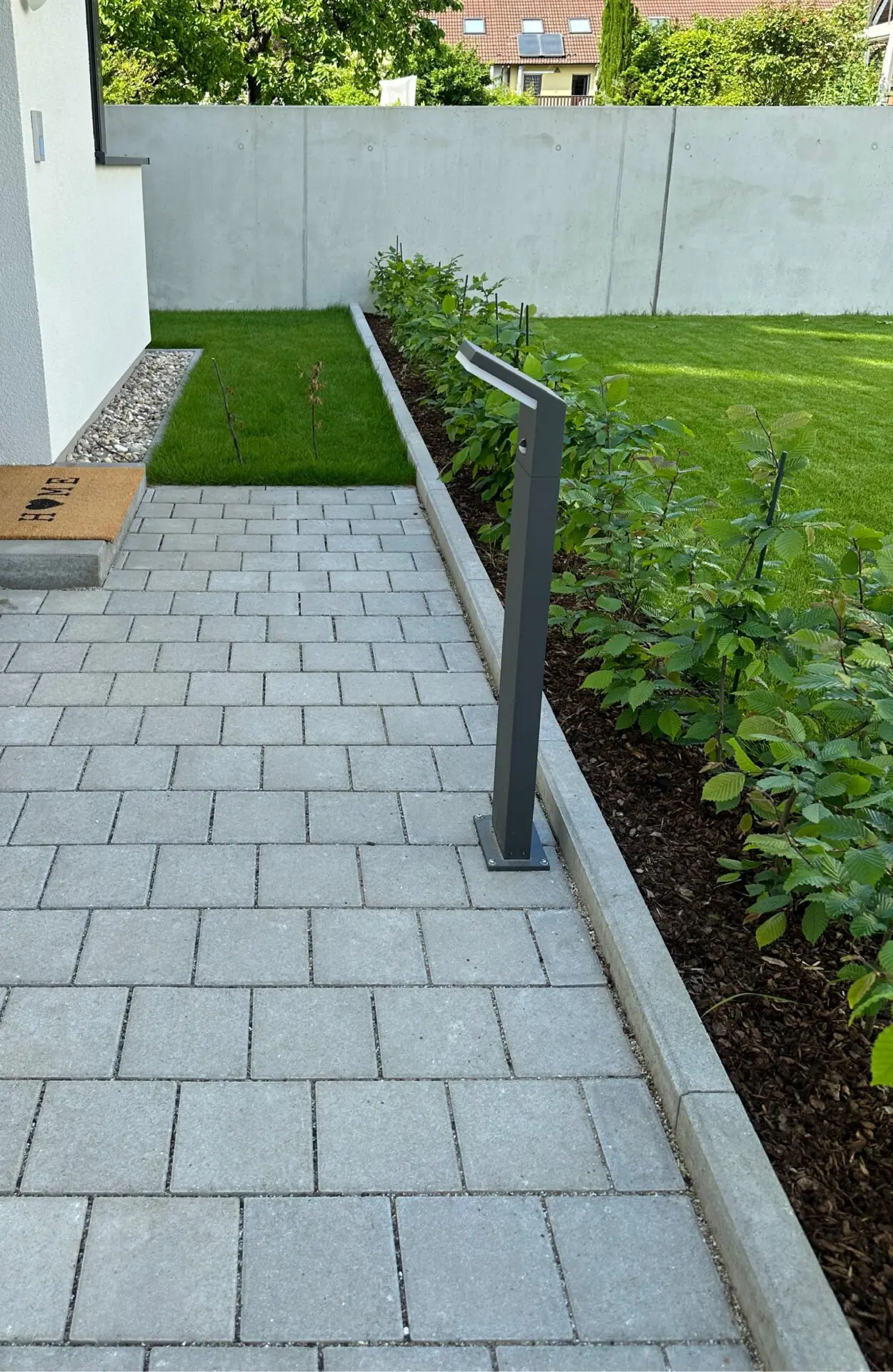 Gestaltung Eingangsbereich Reihenhäuser mit versickerungsfähigem Betonplaster und Außenbeleuchtung sowie Begrünung durch Rollrasen (Classic-Sport) und Hainbuchenhecke.