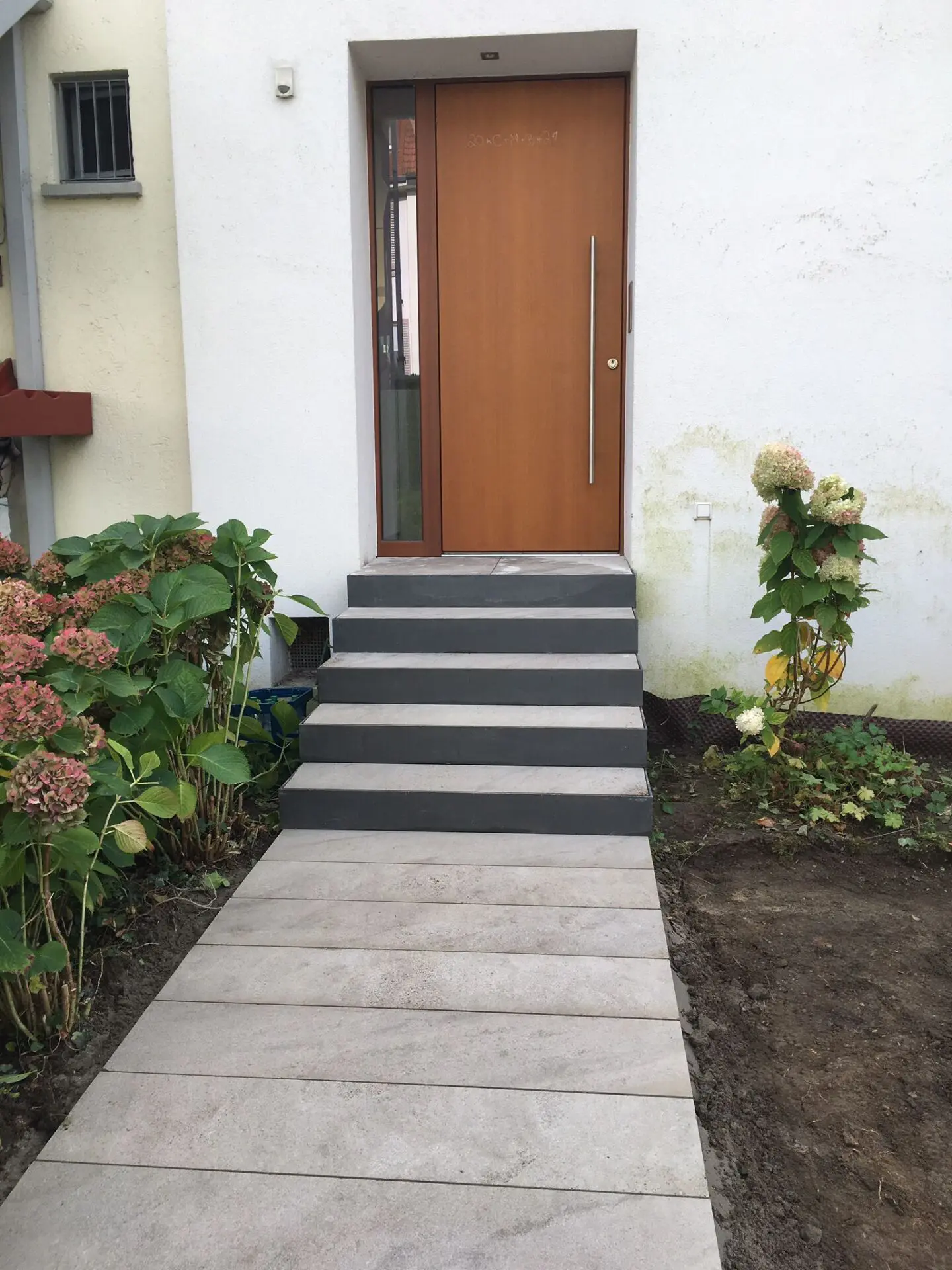 Individuell gefertigte Treppenkonstruktion mit Eingangspodest belegt mit Natursteinplatten für Hauszugang