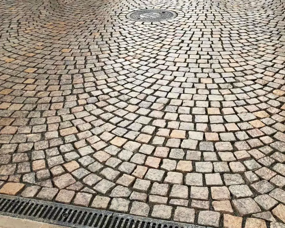 Natursteinkleinpflaster aus italienischen Porphyr. Rotmix. Im Segmentbogen verlegt und Entwässerungsrinne