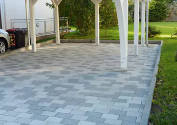Hellgraue Pflasterfläche als Bodenbelag für Carport und Terrasse im Garten